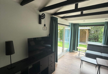 Moderne woonkamer in een lodge met zwarte balken, glazen deuren en zicht op de tuin in Nederland.