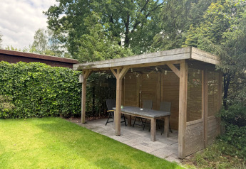 Wooden gazebo with dining table and chairs at «Private» Lodge, Het Verscholen Dorp, Netherlands.