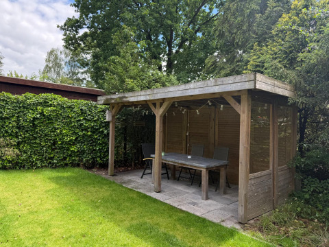 Houten tuinhuis met tafel en stoelen bij «Private» Lodge, Het Verscholen Dorp, Nederland.