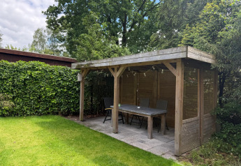 Houten tuinhuis met tafel en stoelen bij «Private» Lodge, Het Verscholen Dorp, Nederland.