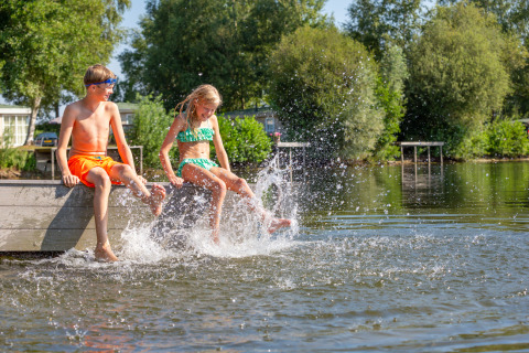 Deux enfants en maillots de bain s'amusent sur un ponton au parc Tolplas, Overijssel, Pays-Bas, en éclaboussant l'eau.