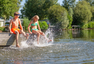 Deux enfants en maillots de bain s'amusent sur un ponton au parc Tolplas, Overijssel, Pays-Bas, en éclaboussant l'eau.