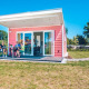 Familie sidder udenfor en lyserød tiny house, Valley Chalet, i Holiday park Ackersate, Holland.