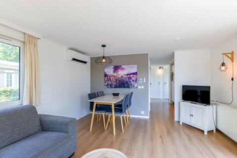 Heller, moderner Wohnbereich im Chalet 4 in Tolplas, Niederlande, mit Esstisch, Sofa und Fernseher.