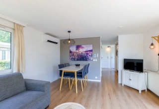 Heller, moderner Wohnbereich im Chalet 4 in Tolplas, Niederlande, mit Esstisch, Sofa und Fernseher.