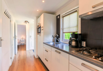 Modern kitchen in Chalet 4 at Tolplas, Netherlands, with stove, coffee maker, and wood flooring.