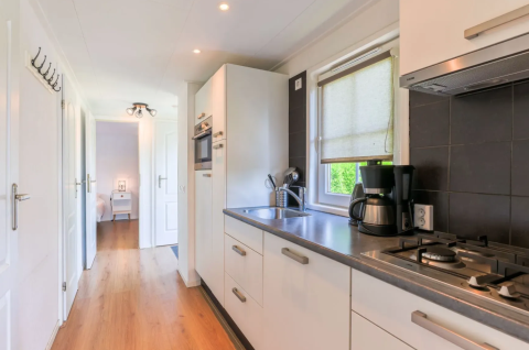 Modernes Kücheninterieur im Chalet 4 am Tolplas, Niederlande, mit Herd, Spüle und Holzfußboden.