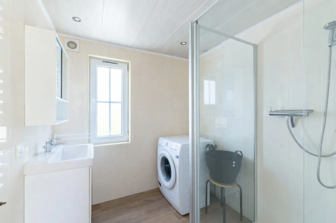 Helles Badezimmer im Chalet 4 am Tolplas, Niederlande, mit Dusche, Waschmaschine und Fenster.