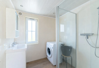 Helles Badezimmer im Chalet 4 am Tolplas, Niederlande, mit Dusche, Waschmaschine und Fenster.
