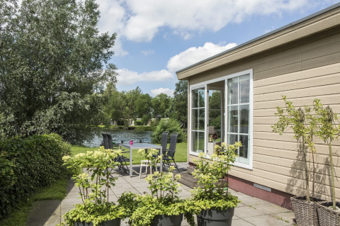 Chalet 4 au Tolplas aux Pays-Bas, terrasse avec table, chaises et vue sur le lac et la verdure.