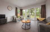 Helles Wohnzimmer in der Linde 4 Sauna in Tolplas, Niederlande, mit moderner Einrichtung und Gartenblick.