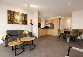 Modern living room with open kitchen, dining table, and wall art at Linde 4 Sauna, Tolplas, Netherlands.