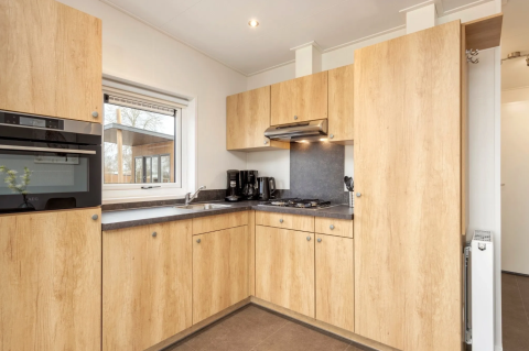 Moderne Küche in der Linde 4 Sauna Lodge am Tolplas, Niederlande, mit Holzschränken und Geräten.