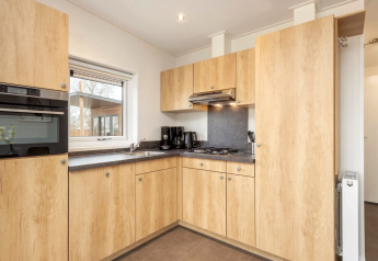Cuisine moderne dans le lodge Linde 4 Sauna à Tolplas, Pays-Bas, avec armoires bois et électroménagers.