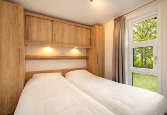 Schlafzimmer in der Linde 4 Sauna Lodge am Tolplas, Niederlande, mit zwei Betten und Holzdekor.