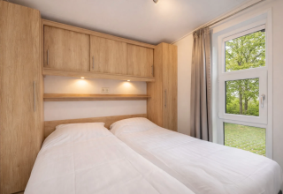 Chambre de la lodge Linde 4 Sauna à Tolplas, Pays-Bas, avec deux lits simples et des meubles en bois clair.