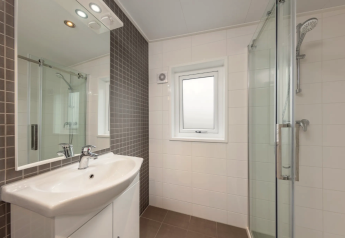 Moderne badkamer in Linde 4 Sauna te Tolplas, Nederland, met douchecabine, wastafel en spiegel.