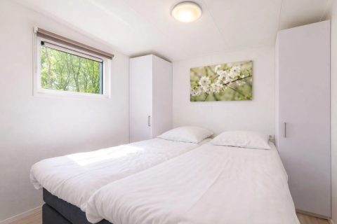 Chambre lumineuse avec deux lits simples, deux armoires, fenêtre et tableau floral, Linde 4 Sauna à Tolplas.