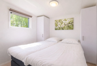 Chambre lumineuse avec deux lits simples, deux armoires, fenêtre et tableau floral, Linde 4 Sauna à Tolplas.