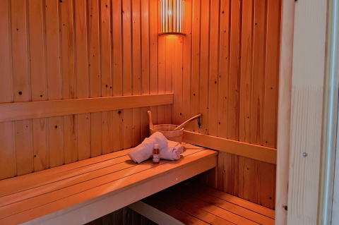 Intérieur d’un sauna au Linde 4 Sauna à Tolplas, Pays-Bas, avec serviette, seau et bouteille.