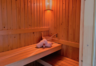 Intérieur d’un sauna au Linde 4 Sauna à Tolplas, Pays-Bas, avec serviette, seau et bouteille.