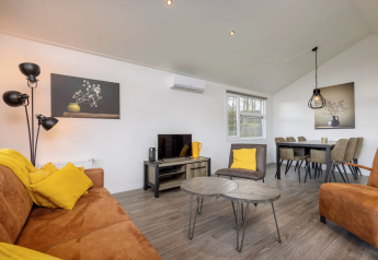 Salon du lodge Schipbeek 6 à Tolplas, Pays-Bas, avec des meubles modernes et une décoration jaune chaleureuse.