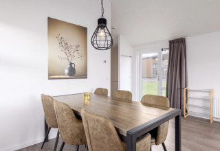 Eethoek in lodge Schipbeek 6 aan de Tolplas, Nederland, met zes stoelen, houten tafel en sfeervolle accenten.
