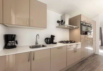 Modern kitchen in lodge Schipbeek 6 at Tolplas, Netherlands, with oven, stove, and coffee maker.