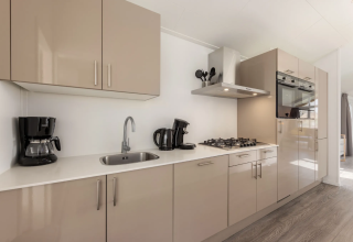 Moderne keuken in lodge Schipbeek 6 aan Tolplas in Nederland, met oven, kookplaat en koffiemachine.