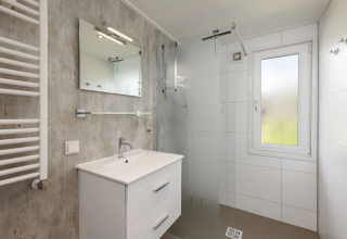 Salle de bain moderne à Schipbeek 6, Tolplas, Pays-Bas, avec douche, lavabo, miroir et fenêtre.