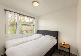 Schlafzimmer der Schipbeek 6 Lodge bei Tolplas, Niederlande, mit zwei Einzelbetten und Fenster.