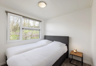 Schlafzimmer der Schipbeek 6 Lodge bei Tolplas, Niederlande, mit zwei Einzelbetten und Fenster.