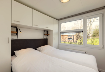 Schlafzimmer in der Lodge Schipbeek 6 in Tolplas, Niederlande, mit Doppelbett und Panoramafenstern.