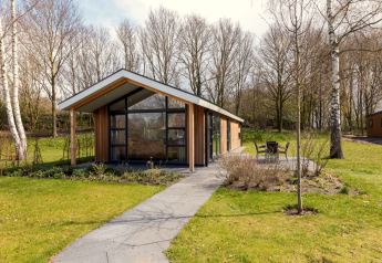Die Schipbeek 6 Lodge am Tolplas in den Niederlanden mit moderner Architektur, Terrasse und grünem Garten.