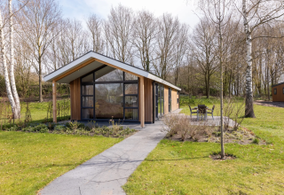 Die Schipbeek 6 Lodge am Tolplas in den Niederlanden mit moderner Architektur, Terrasse und grünem Garten.