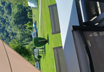 Vue depuis la tente safari Coco Sweet au Camping Floreal La Roche-en-Ardenne avec chaises et pelouse verte.
