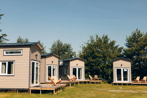 Four cozy Koya Tiny Loft houses at Wilsumer Berge in Germany with wooden decks and nature surroundings.