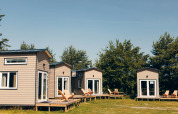 Petites maisons Koya Tiny Loft à Wilsumer Berge, Allemagne, dotées de terrasses avec chaises et entourées de verdure.