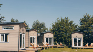 Vier Koya Tiny Loft huizen op Wilsumer Berge in Duitsland met houten veranda’s en omringd door natuur.