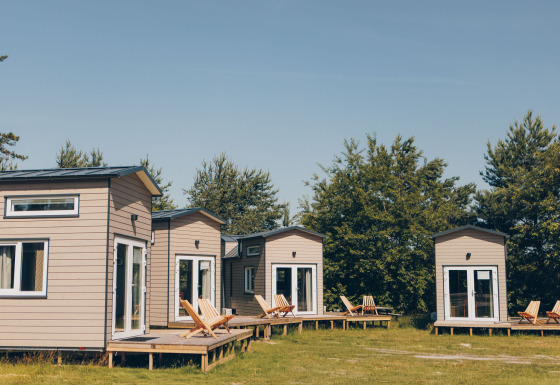 Four cozy Koya Tiny Loft houses at Wilsumer Berge in Germany with wooden decks and nature surroundings.