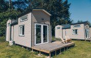 Foto van de 'Koya Tiny Loft' tiny houses bij Wilsumer Berge in Duitsland, met houten terras en groen eromheen.