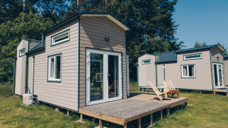 Billedet viser de små hytter kaldet 'Koya Tiny Loft' ved Wilsumer Berge i Tyskland, omgivet af natur.