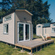 A photo of the 'Koya Tiny Loft' tiny houses at Wilsumer Berge, Germany, featuring wooden decks and trees.