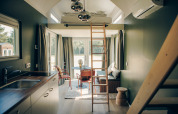 Intérieur moderne et lumineux du Koya Tiny Loft en Allemagne avec mezzanine, échelle, cuisine et coin repas cosy.