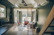Modern, licht interieur van het Koya Tiny Loft tiny house in Duitsland met slaapzolder, ladder en zitgedeelte.