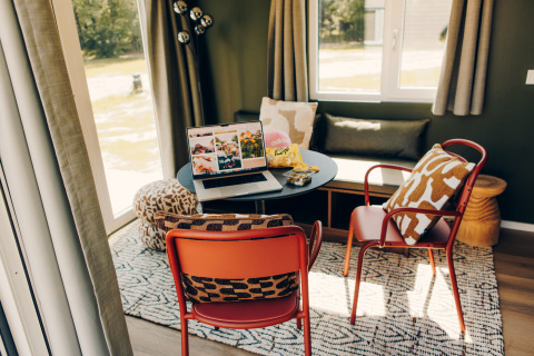 Cozy workspace in Koya Tiny Loft, Wilsumer Berge, Germany featuring a laptop, chairs, and pillows.