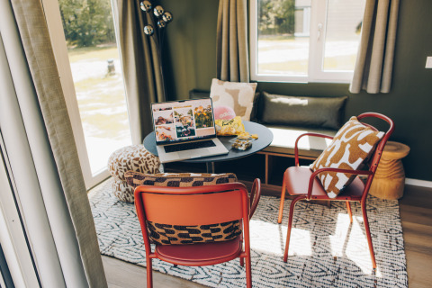 Cozy workspace in Koya Tiny Loft, Wilsumer Berge, Germany featuring a laptop, chairs, and pillows.