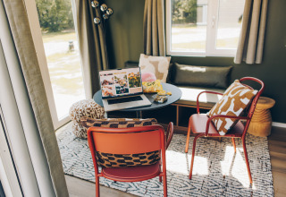 Cozy workspace in Koya Tiny Loft, Wilsumer Berge, Germany featuring a laptop, chairs, and pillows.