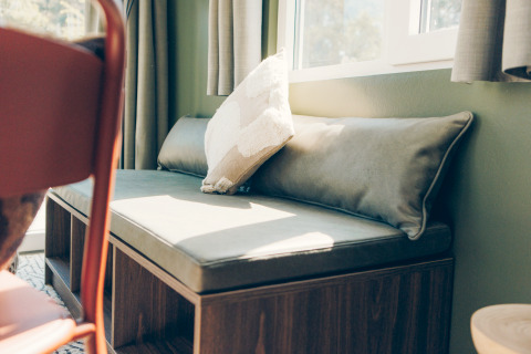 Sunny bench seating with plush cushions by the window in Koya Tiny Loft, Wilsumer Berge, Germany.
