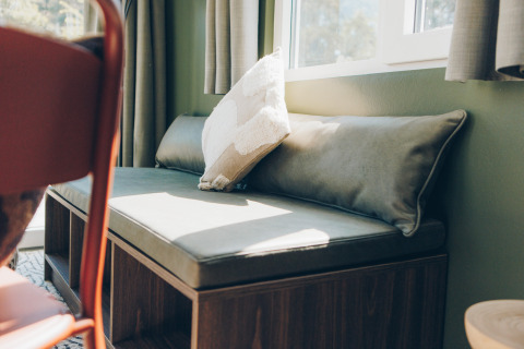 Sunny bench seating with plush cushions by the window in Koya Tiny Loft, Wilsumer Berge, Germany.